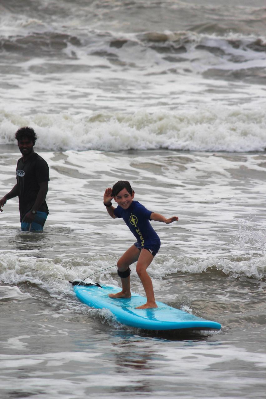 A young student riding a wave while the instructor watches